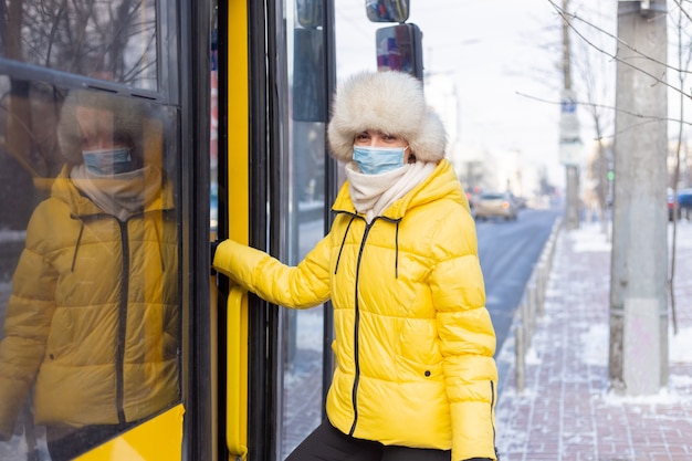 Mujer sonriente joven entra en el autobús en un día de invierno