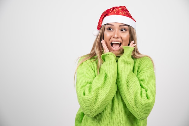 Mujer sonriente joven posando con sombrero rojo de Santa Claus.