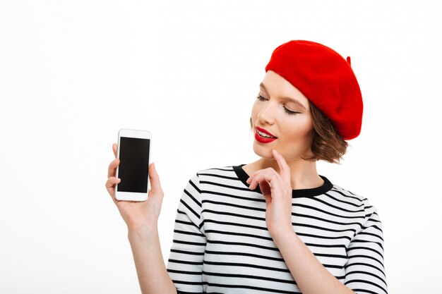 Mujer sonriente joven que muestra la exhibición del teléfono móvil.