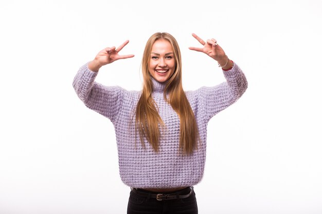 Mujer sonriente joven que muestra la victoria o el signo de la paz aislado