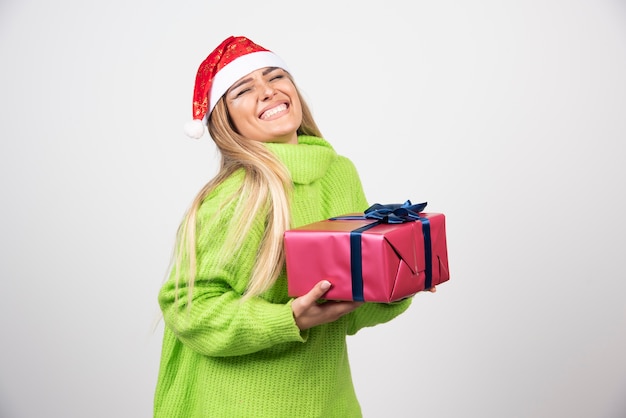 Mujer sonriente joven que sostiene un regalo de Navidad festivo.