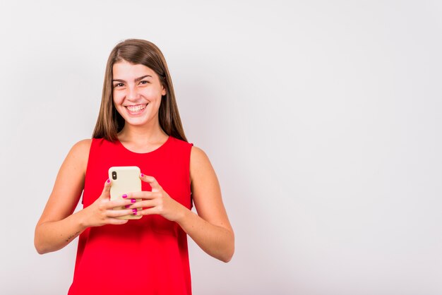 Mujer sonriente joven que sostiene el teléfono móvil