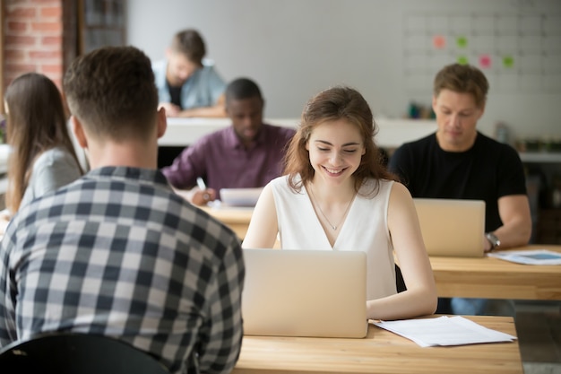 Foto gratuita mujer sonriente joven que trabaja en la computadora portátil en espacio de oficina coworking