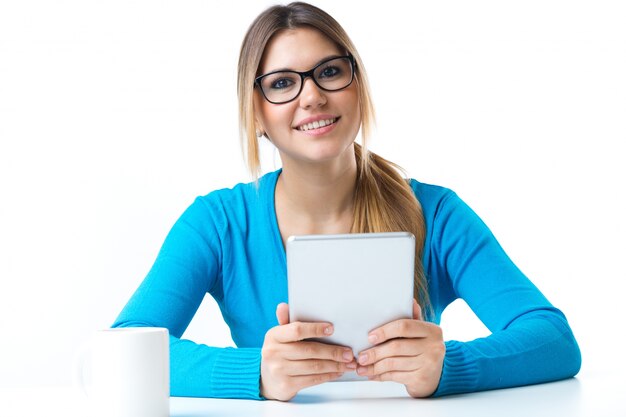 Mujer sonriente joven que usa la tableta digital. Aislado en blanco.