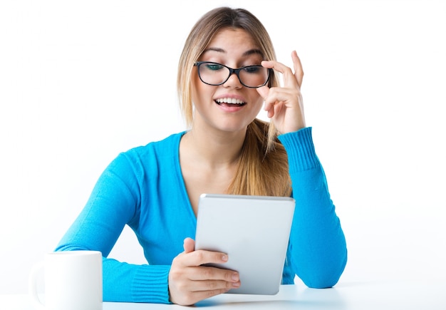 Mujer sonriente joven que usa la tableta digital. Aislado en blanco.