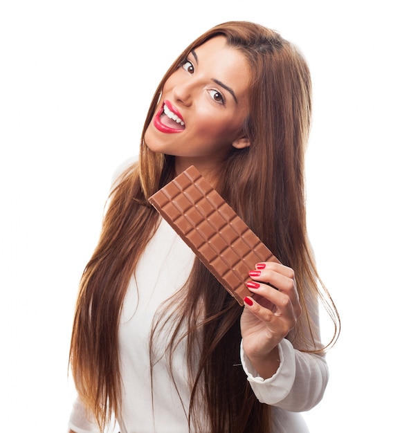 mujer sonriente joven que visualiza la barra de chocolate.