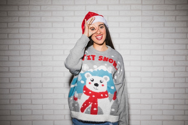 Mujer sonriente joven en el sombrero y el suéter de la Navidad