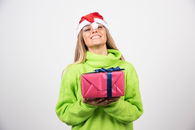 Mujer sonriente joven sosteniendo un regalo de Navidad festivo