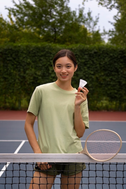 Mujer sonriente jugando bádminton vista frontal