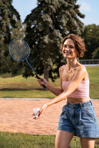 Foto gratuita mujer sonriente jugando bádminton vista lateral