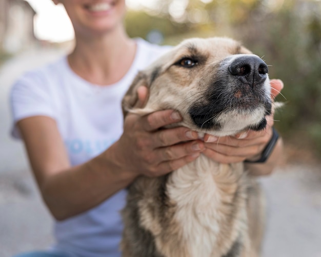 Mujer sonriente jugando con lindo perro al aire libre