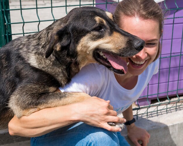 Mujer sonriente jugando con perro en adopción