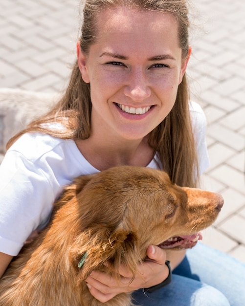 Mujer sonriente jugando con perro en refugio