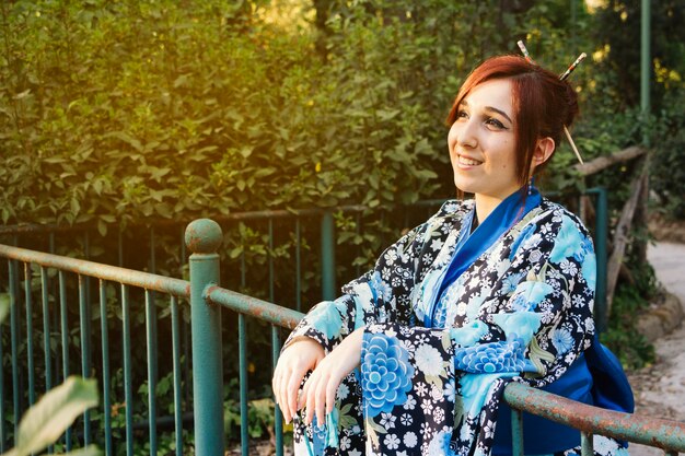 Mujer sonriente en kimono cerca de la cerca