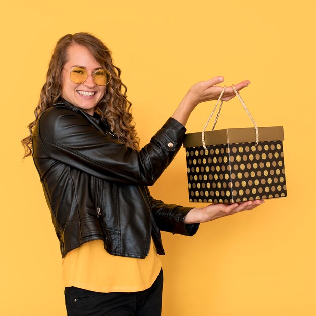 Mujer sonriente de lado con caja de regalo de viernes negro