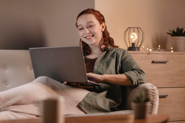 Mujer sonriente con laptop en casa en el sofá