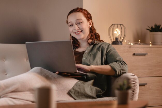 Mujer sonriente con laptop en casa en el sofá