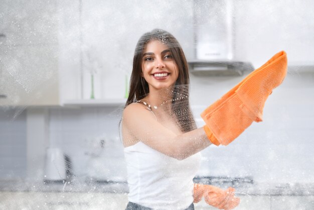 Mujer sonriente, lavado, ventana, con, trapo