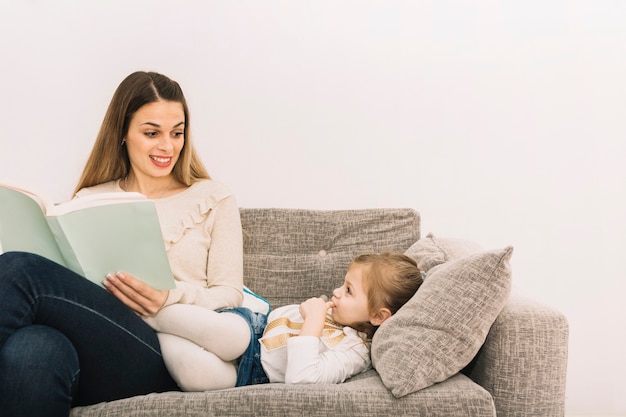 Mujer sonriente leyendo cuento de hadas a hija