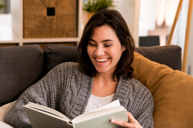 Mujer sonriente leyendo en la sala de estar