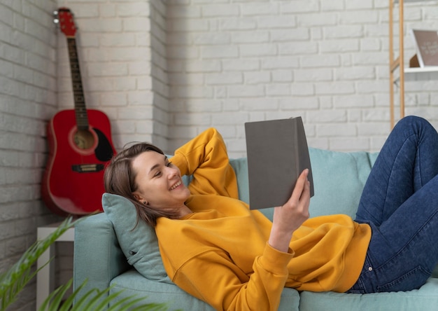 Foto gratuita mujer sonriente leyendo en el sofá