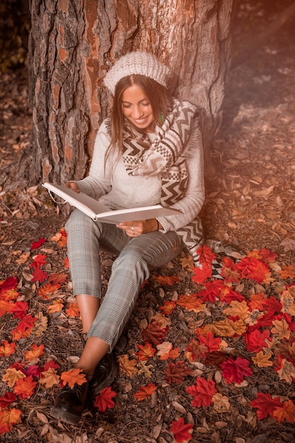 Mujer sonriente leyendo en el suelo