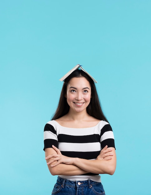 Mujer sonriente con libro en cabeza