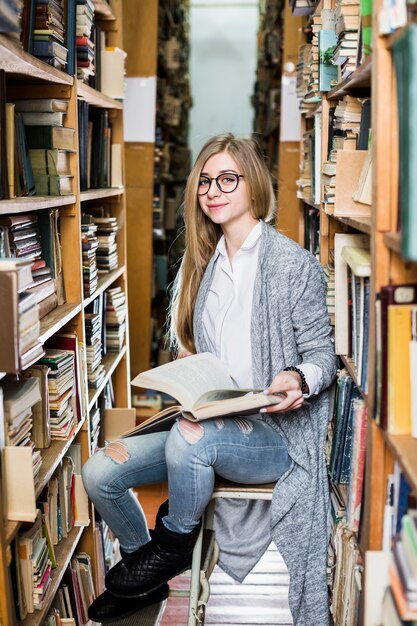 Mujer sonriente con libro sentado en taburete