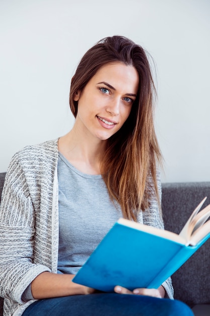 Foto gratuita mujer sonriente con libro en el sofá