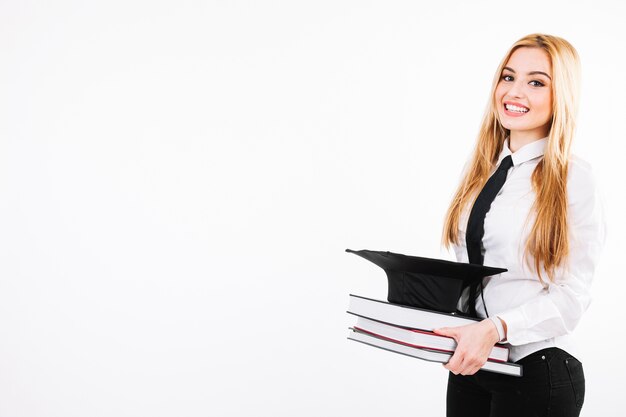 Mujer sonriente con libros y mortarboard