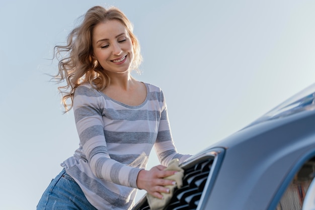 Foto gratuita mujer sonriente limpiando su coche fuera