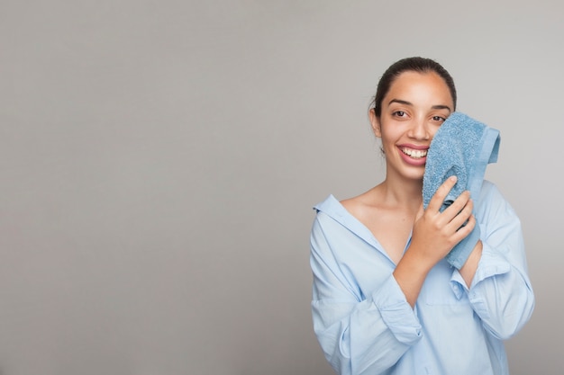 Mujer sonriente limpiándose la cara y espacio para copiar