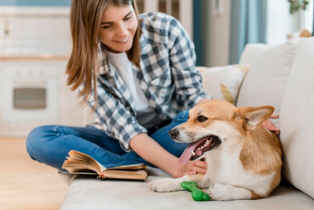 Mujer sonriente con lindo perro en el sofá