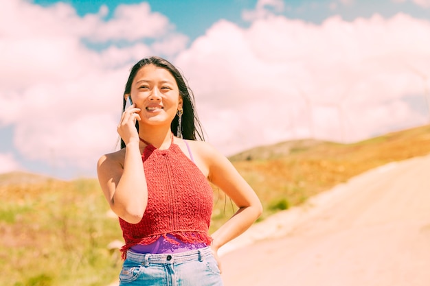 Mujer sonriente llamando por teléfono en campo