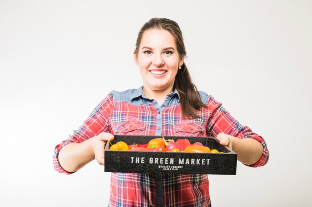 Mujer sonriente llevando tomates y pimientos