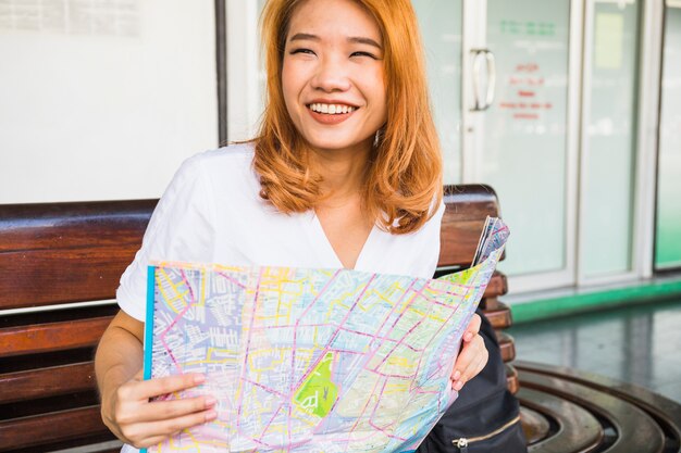 Mujer sonriente con el mapa en el banco