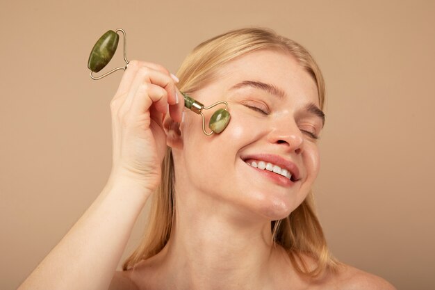 Mujer sonriente masajeando la cara con la herramienta de cerca