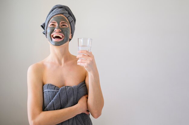 Mujer sonriente con mascarilla en la celebración de vaso de agua