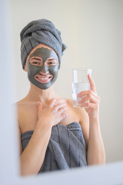 Mujer sonriente con mascarilla y sosteniendo un vaso de agua