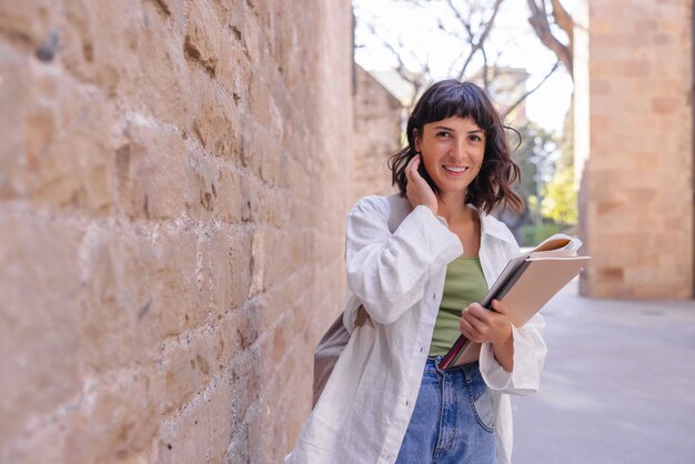 Mujer sonriente mira la cámara con libros de trabajo