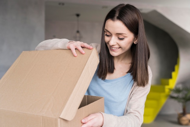 Mujer sonriente mirando en caja de cartón