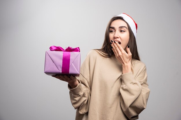 Mujer sonriente mirando una caja de regalo de Navidad.