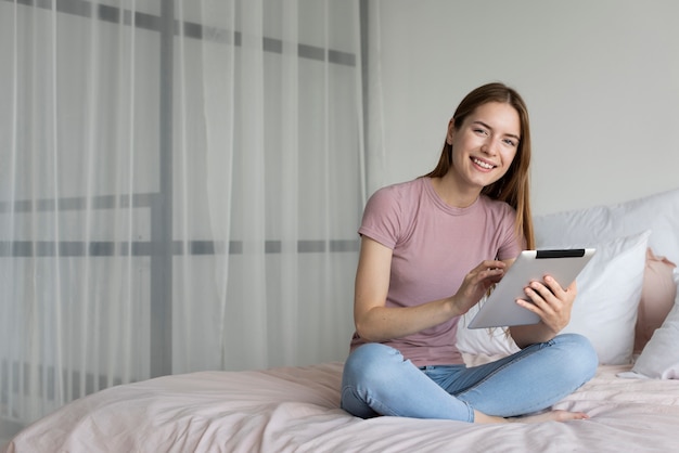 Foto gratuita mujer sonriente mirando a través de su tableta