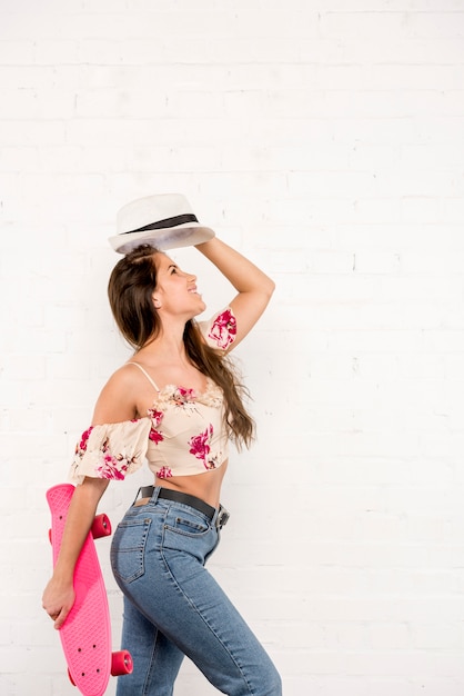 Foto gratuita mujer sonriente con el monopatín y el sombrero rosados