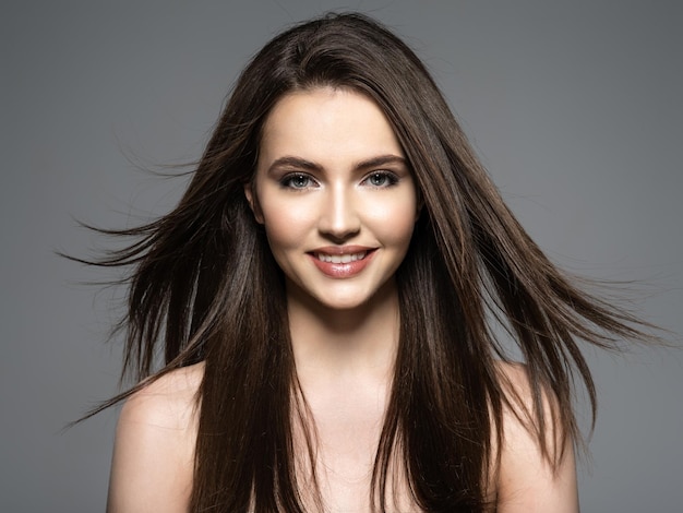 Foto gratuita mujer sonriente morena con cabello largo castaño de belleza. modelo de moda con pelo largo y liso. modelo de moda posando. mujer bonita con cabello castaño largo y recto.