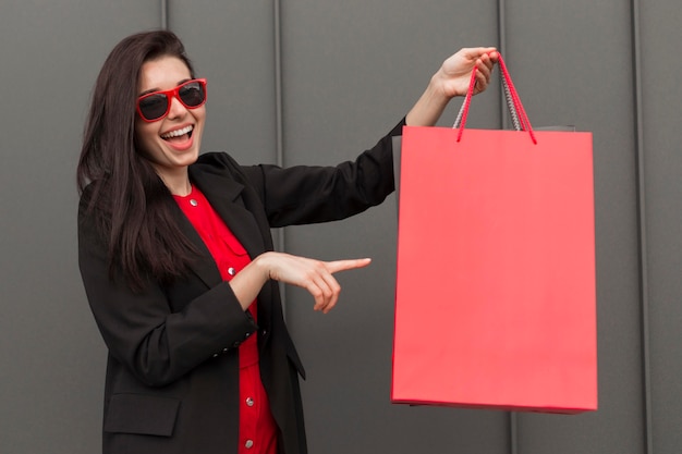 Mujer sonriente mostrando una bolsa de compras de espacio de copia roja