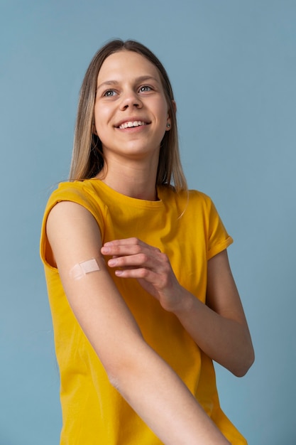 Mujer sonriente mostrando el brazo con la etiqueta engomada después de recibir una vacuna