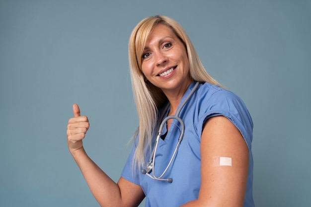 Mujer sonriente mostrando el brazo con la etiqueta engomada después de recibir una vacuna