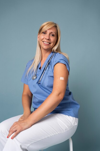 Foto gratuita mujer sonriente mostrando el brazo con la etiqueta engomada después de recibir una vacuna