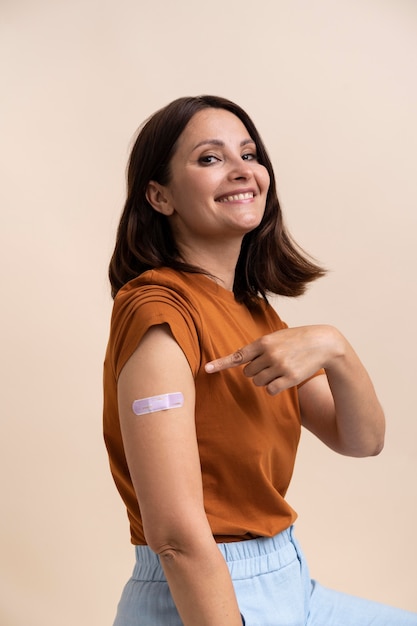 Mujer sonriente mostrando pegatina en el brazo después de recibir una vacuna